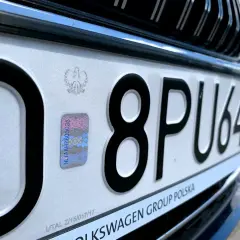 Zbliżenie na polską tablicę rejestracyjną z numerem 8PU64 i hologramem.