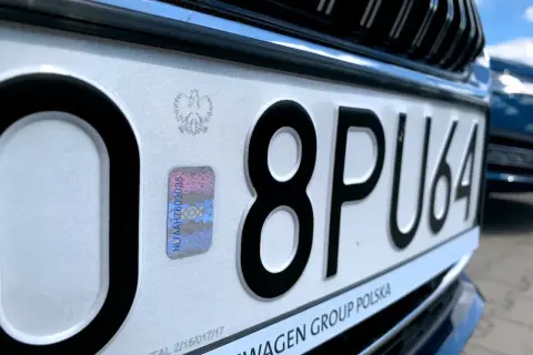 Zbliżenie na polską tablicę rejestracyjną z numerem 8PU64 i hologramem.
