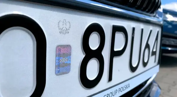 Zbliżenie na polską tablicę rejestracyjną z numerem 8PU64 i hologramem.