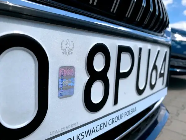Zbliżenie na polską tablicę rejestracyjną z numerem 8PU64 i hologramem.